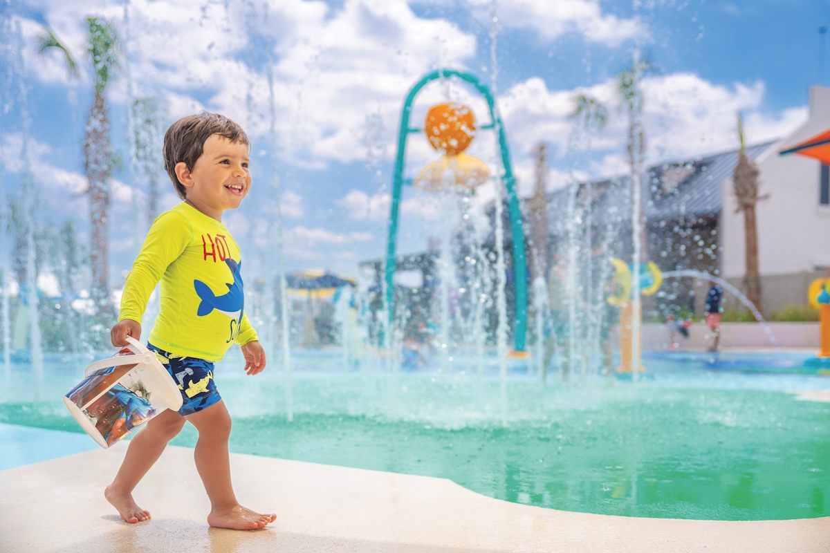 little boy with bucket of water at a splash zone park