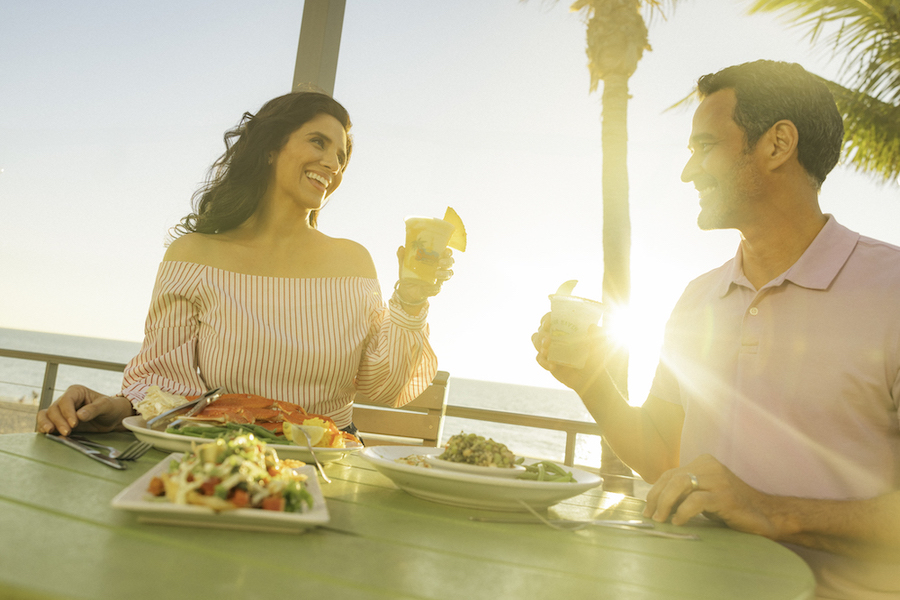 couple cheersing drinks at sunset by the water