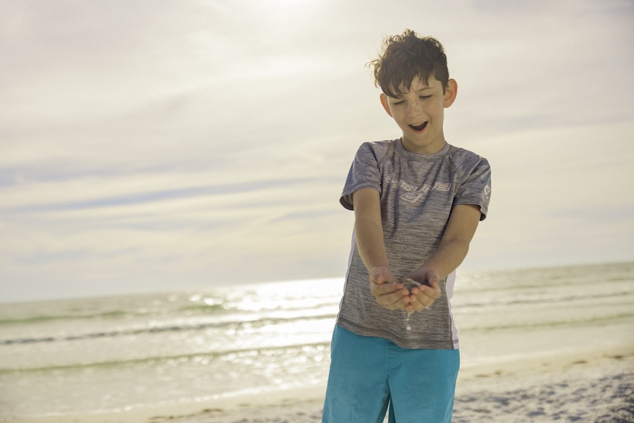 boy finding sea treasures in the sand at siesta beach