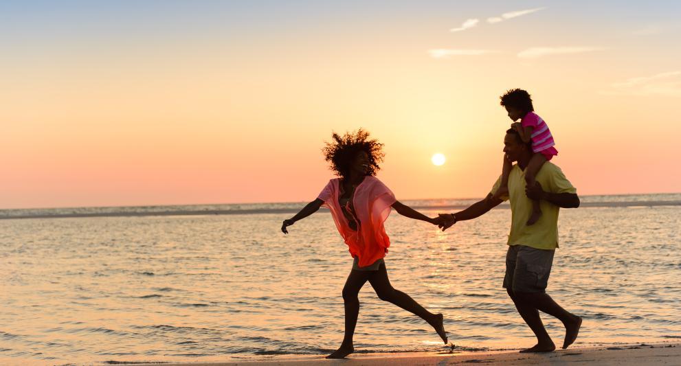 family laughing at sunset running down the beach