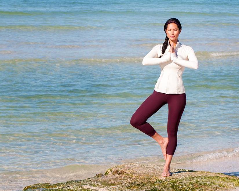 Woman on a Sarasota beach by the water in yoga pose.