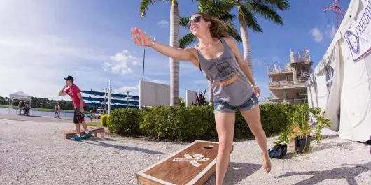 Girl playing cornhole in the fall breeze at one of Sarasota's Oktoberfest events.