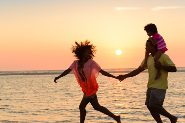 Family running on the beach at sunset