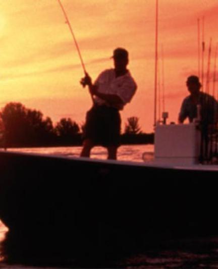 Two fishers on boats casting lines at dawn