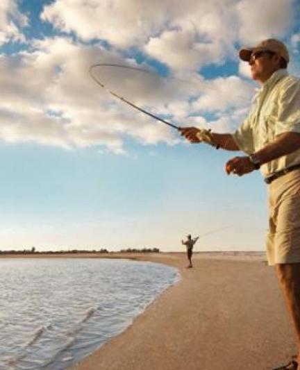 Man fishing at sunset on the beach.