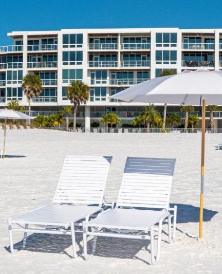 Beach chairs on the beach with umbrella and condo building in the background