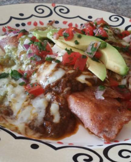 Pan-fried blue corn crepe cheese enchiladas stuffed with chevre, Monterey Jack and Mexican queso, and topped with ranchero sauce, sliced avocado, sour cream and salsa.. Photo Credit: Abby Weingarten.
