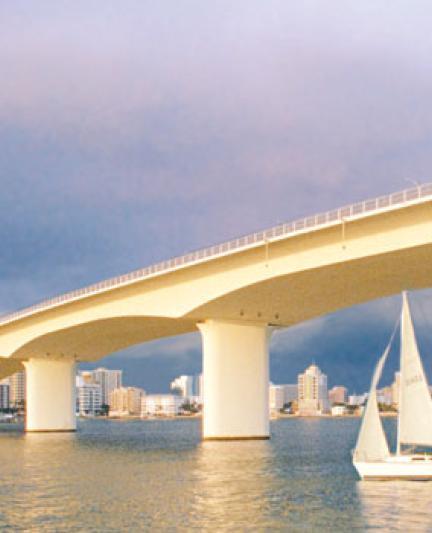 Ringling Bridge at dusk, as a small boat passes beneath the arches