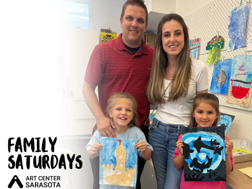 A family with two children holding up their artwork