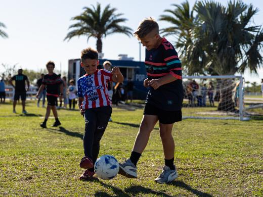 To kids kicking a soccer ball