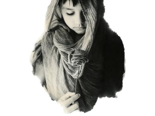 Black and white image of a young, solemn-looking boy with dark hair. His head is covered in a textured middle-eastern style scarf and he's looking down at a rose he's holding.