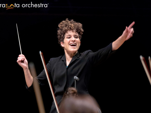 Sarasota Orchestra conductor smiles with a baton