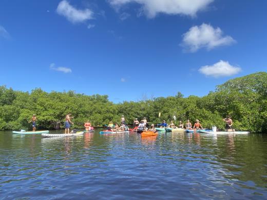 Group of people kayaking and paddleboarding during a beach clean up event