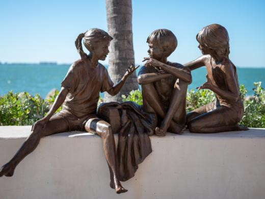 Facts of Life sculpture by Glenna Goodacre - Life-size sculpture of three children sitting on a wall having a conversation. Glenna Goodacre was an American sculptor best known for having designed t... Photo 6