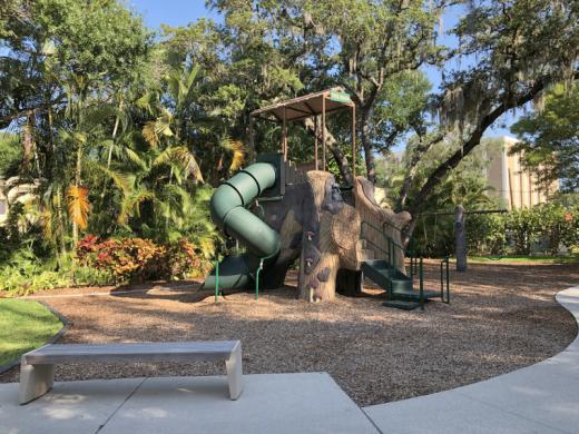 Laurel Park Playground - Includes a central tree trunk with two spiral slides and climbing areas. There is also a  swing set, sand box and grassy play area. Photo