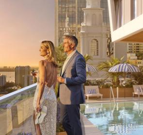 Couple standing by rooftop pool watching sunset