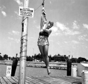 Tarpon queen Barbara Glidden poses for a photograph while hanging from a weighing device - Sarasota, Florida 1962.jpg