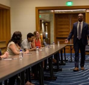 Man speaks to group at table