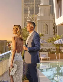 Couple standing by rooftop pool watching sunset