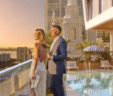 Couple standing by rooftop pool watching sunset