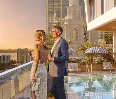 Couple standing by rooftop pool watching sunset