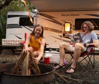 Couple in camping chairs outside RV
