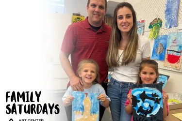 A family with two children holding up their artwork