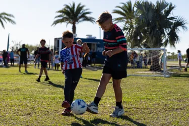To kids kicking a soccer ball