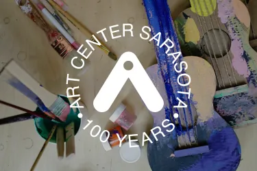 image of a cardboard guitar, half painted, with Art Center Sarasota logo