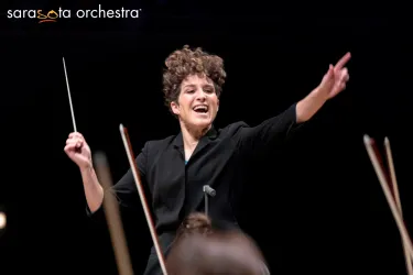 Sarasota Orchestra conductor smiles with a baton