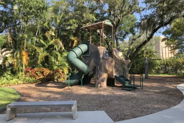 Laurel Park Playground - Includes a central tree trunk with two spiral slides and climbing areas. There is also a  swing set, sand box and grassy play area. Photo